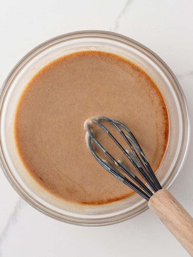 Cinnamon filling whisked together in a glass bowl for cinnamon roll poke cake.