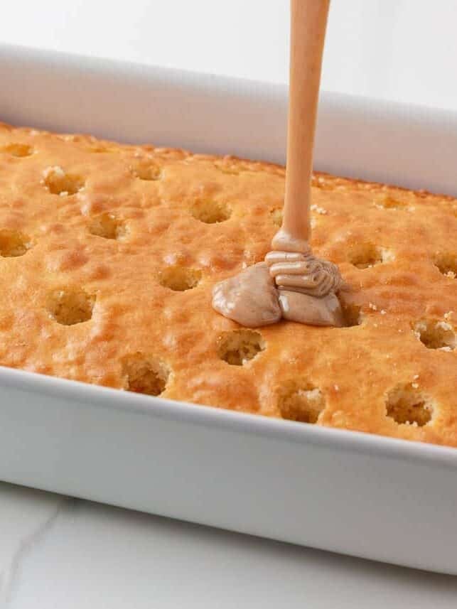 Pouring cinnamon condensed milk filling into holes in the baked cake.