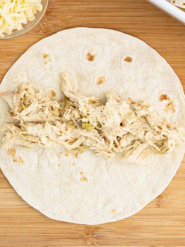 Creamy green chile chicken filling spooned across the center of a flour tortilla.