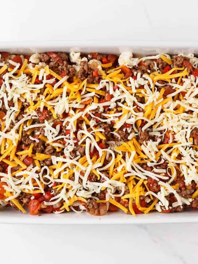Hamburger casserole topped with shredded cheddar and mozzarella before baking.