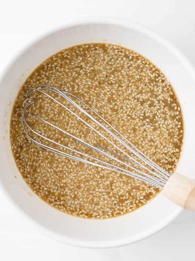 Honey sesame sauce in a bowl with a whisk.