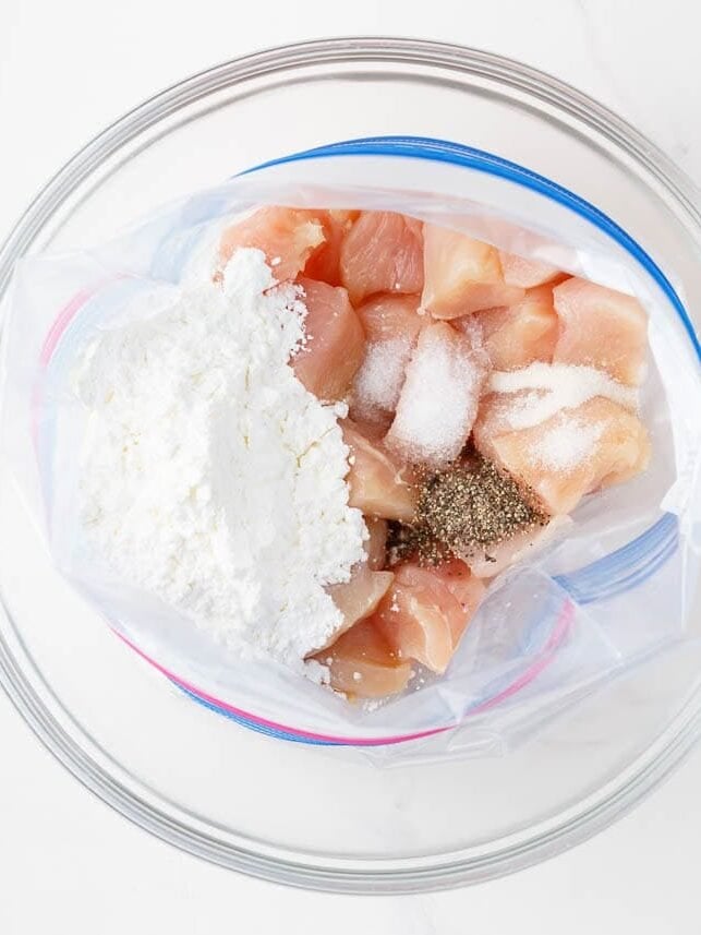 Coating chicken pieces in flour.