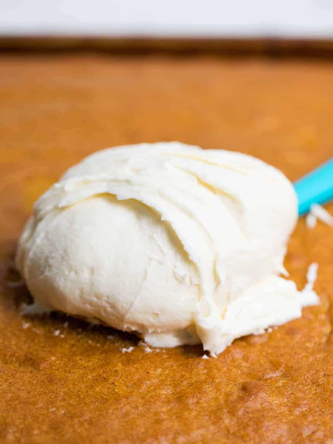 Cream cheese frosting being spread on pumpkin bars.