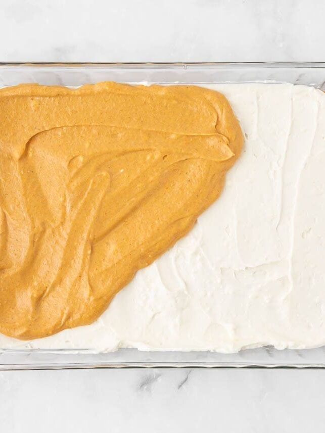 Spreading pumpkin cheesecake filling over the cream cheese layer.