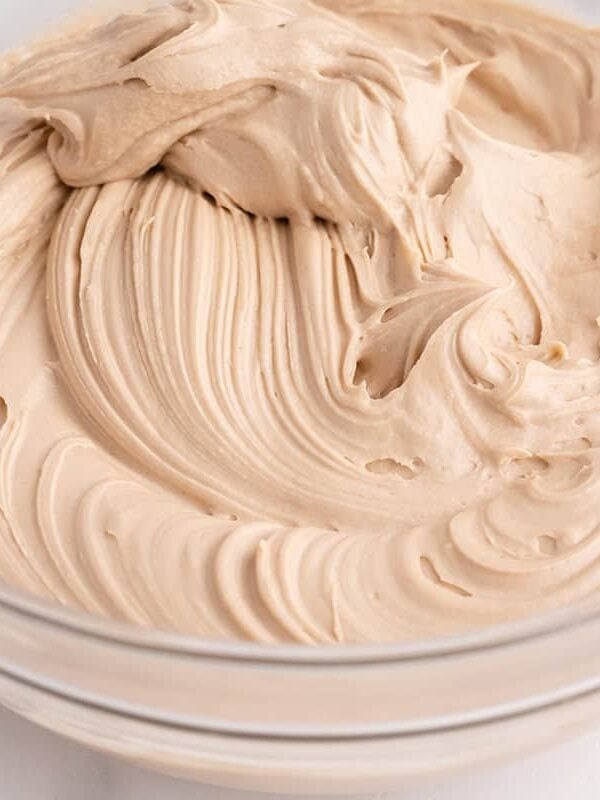 Maple cream cheese frosting in a glass bowl ready for piping onto pumpkin spice cupcakes.