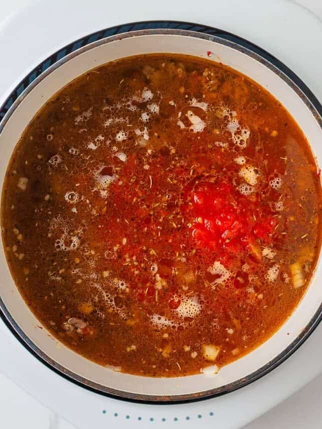Chicken broth and diced tomatoes added to Italian sausage mixture for tortellini soup.