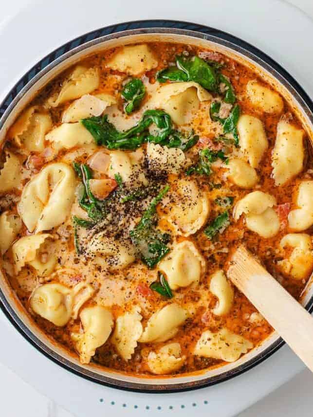 Creamy Tuscan tortellini soup with sausage, spinach and tomatoes in a Dutch oven.