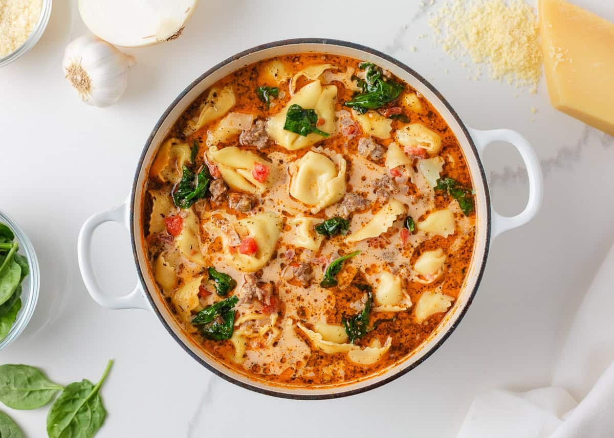 Creamy tortellini soup with spinach, sausage and tomatoes finished in a Dutch oven.