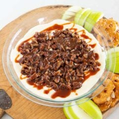 Pecan pie dip topped with chopped pecans and caramel, served with apple slices and pretzels.