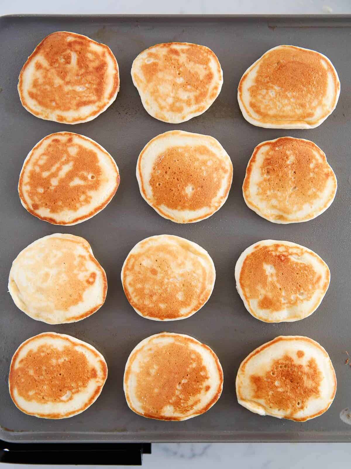 Silver dollar pancakes cooking on the griddle.
