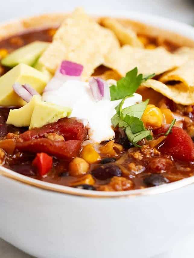 Turkey chili in a white bowl with toppings.