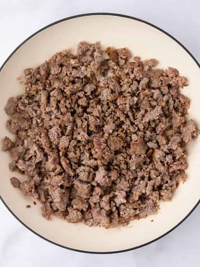 Cooking sausage on a white pot.