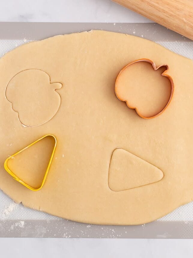 Cutting sugar cookie dough out with Halloween cookie cutters.