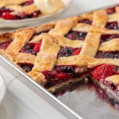 Berry slab pie with golden lattice crust and mixed berry filling baked on a sheet pan.