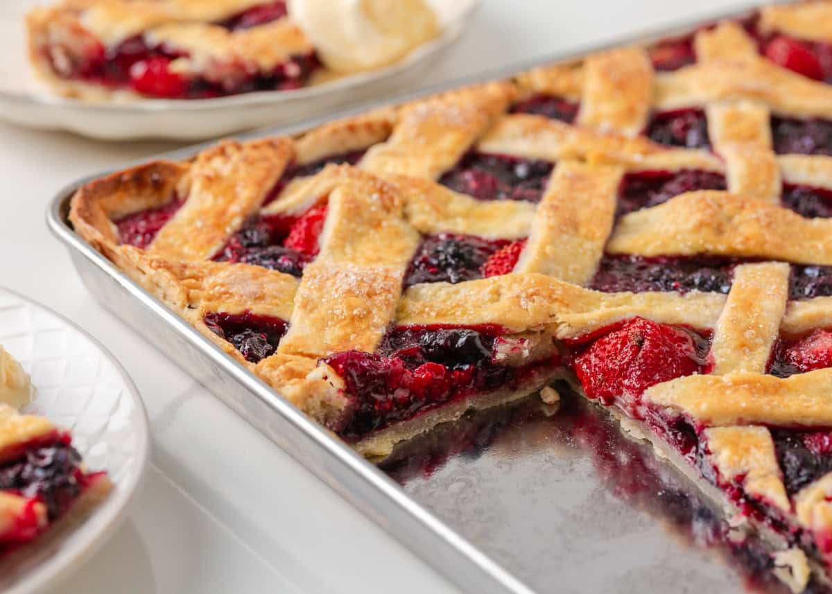 Berry slab pie with golden lattice crust and mixed berry filling baked on a sheet pan.