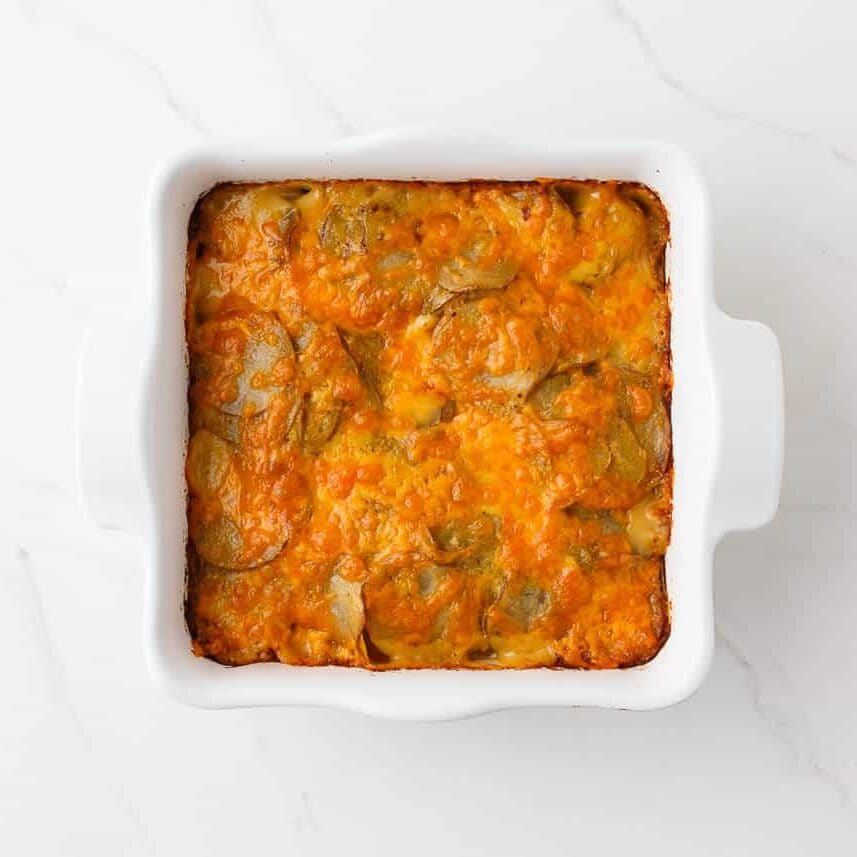 Baked potatoes au gratin with tender sliced potatoes and golden, bubbly melted cheese in a white baking dish.