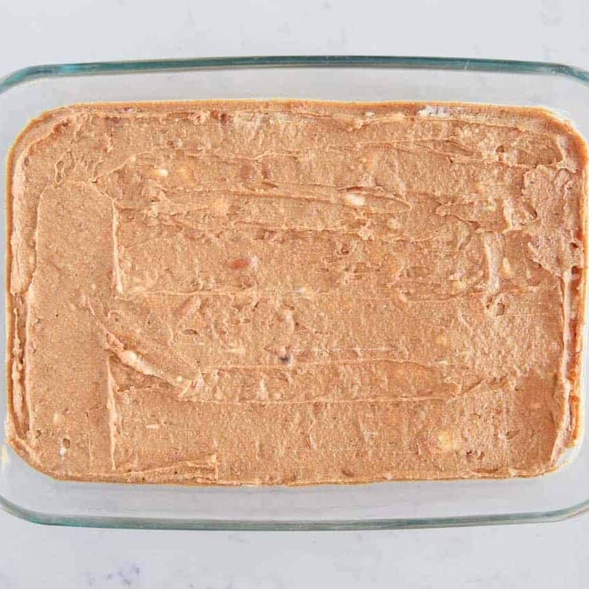 Refried beans at the bottom of a glass dish for the base of 7 layer dip.