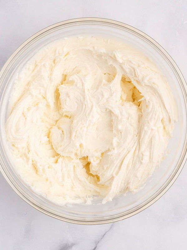 Buttercream frosting whipped in a glass bowl.