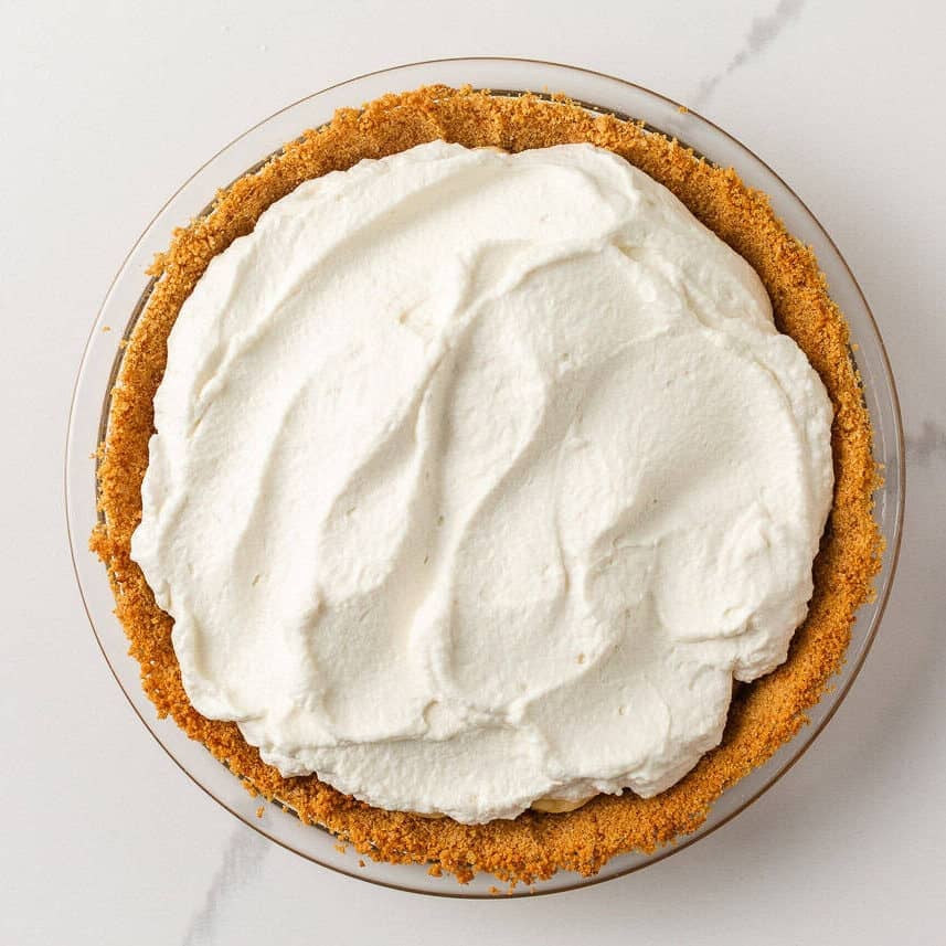 Whipped cream spread over the banana and dulce de leche filling.