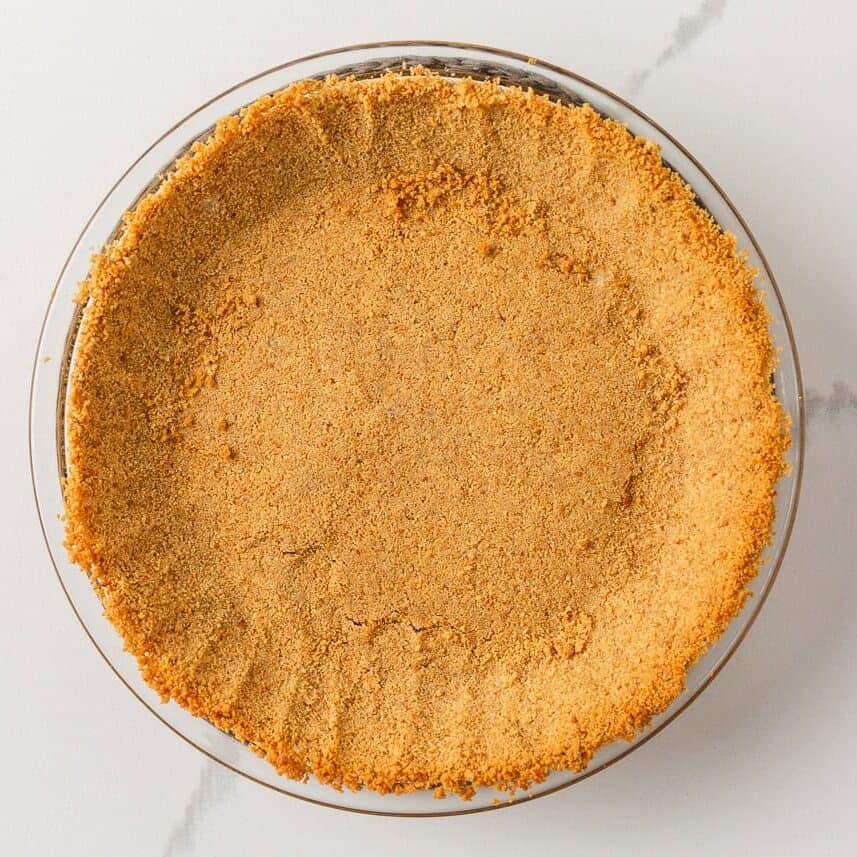 Homemade graham cracker crust pressed into a glass pie plate.