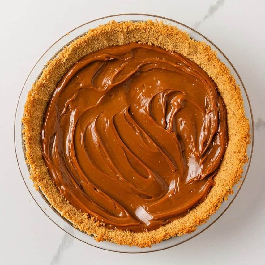 Dulce de leche spread evenly inside the graham cracker pie crust.