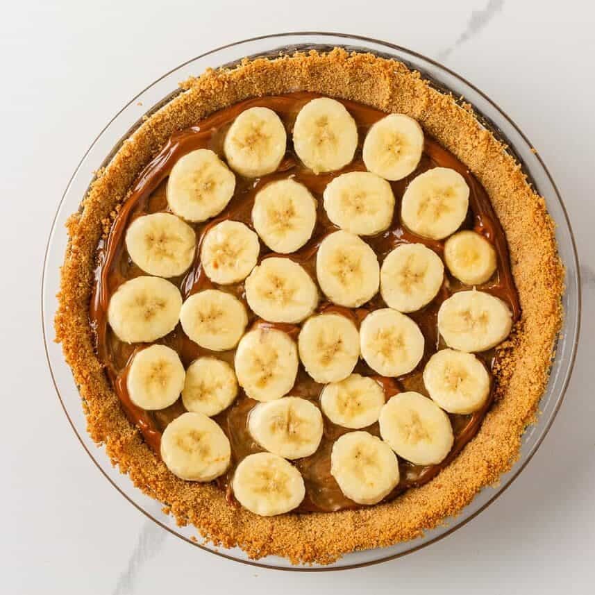 Sliced bananas arranged over the dulce de leche layer in a graham cracker crust.