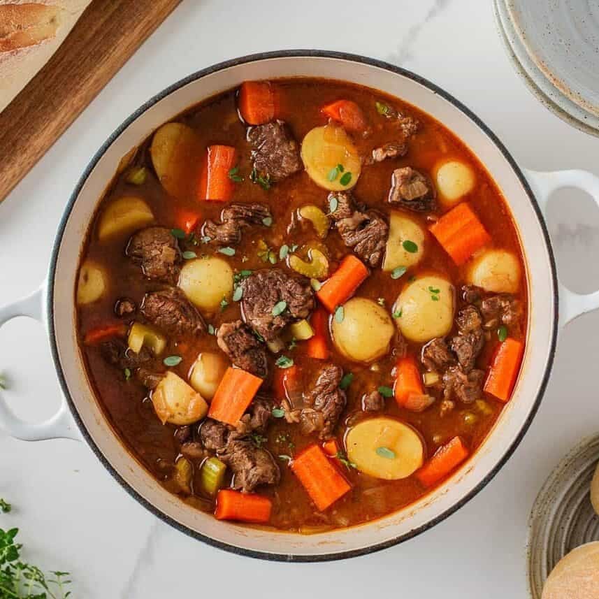 Chuck roast beef stew in a Dutch oven with tender beef, potatoes, carrots and celery.