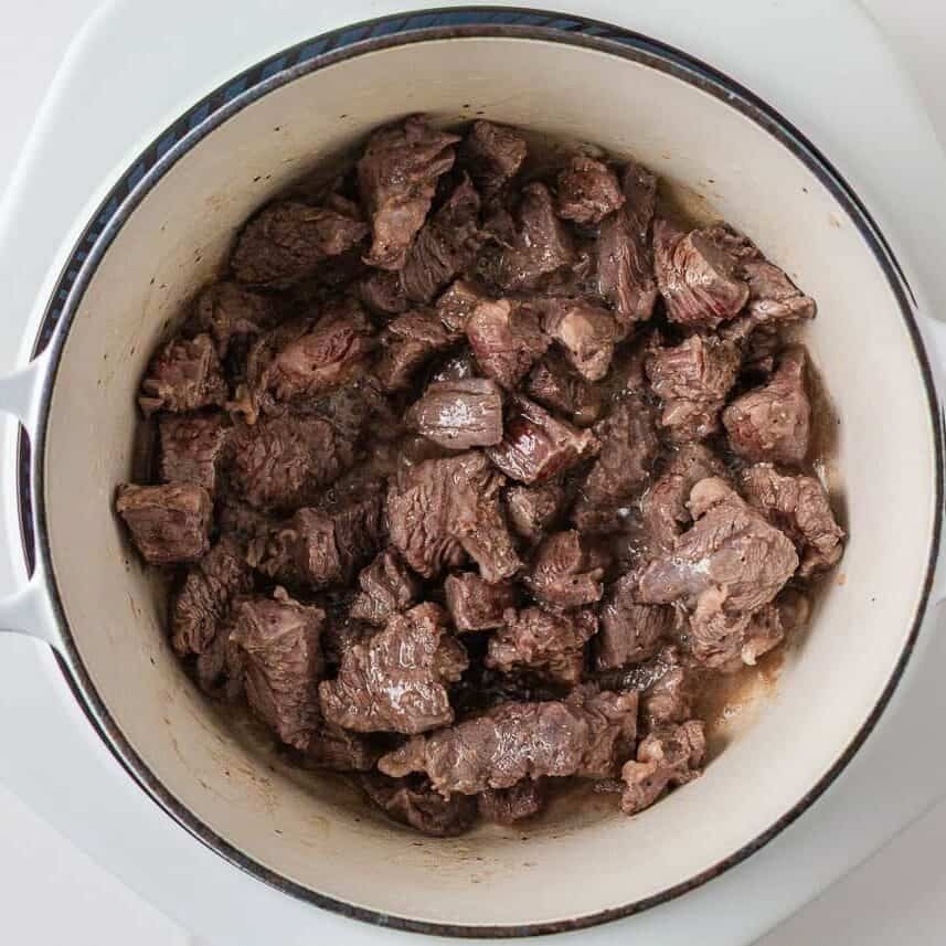 Cubed chuck roast searing in a Dutch oven for homemade beef stew.