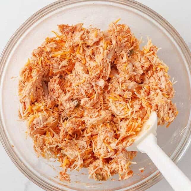 Shredded chicken and cheese taco filling mixed in a glass bowl.