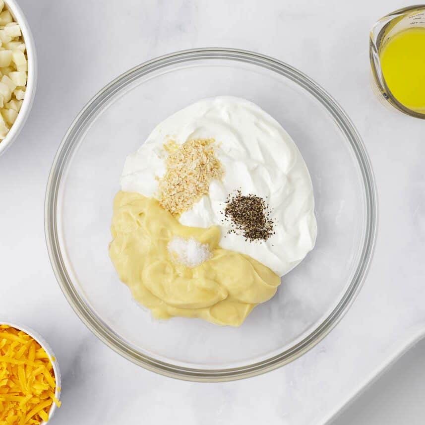 Sour cream, cream of chicken soup, melted butter, and seasonings whisked together in a glass mixing bowl.