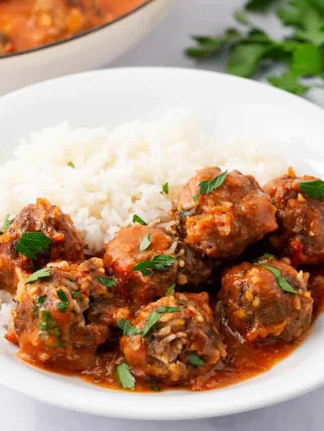 Porcupine meatballs in tomato sauce served over white rice and garnished with parsley.