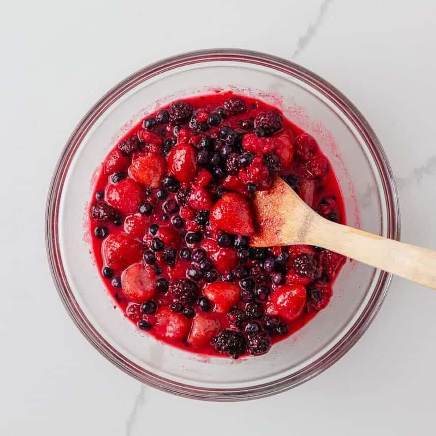 Strawberries, blueberries, raspberries and blackberries mixed with sugar for berry pie filling.