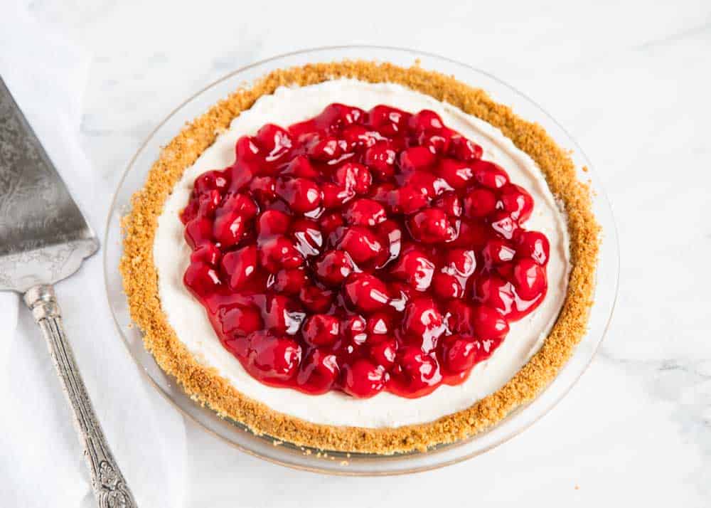 No bake cheesecake in pan with cherry filling on top.