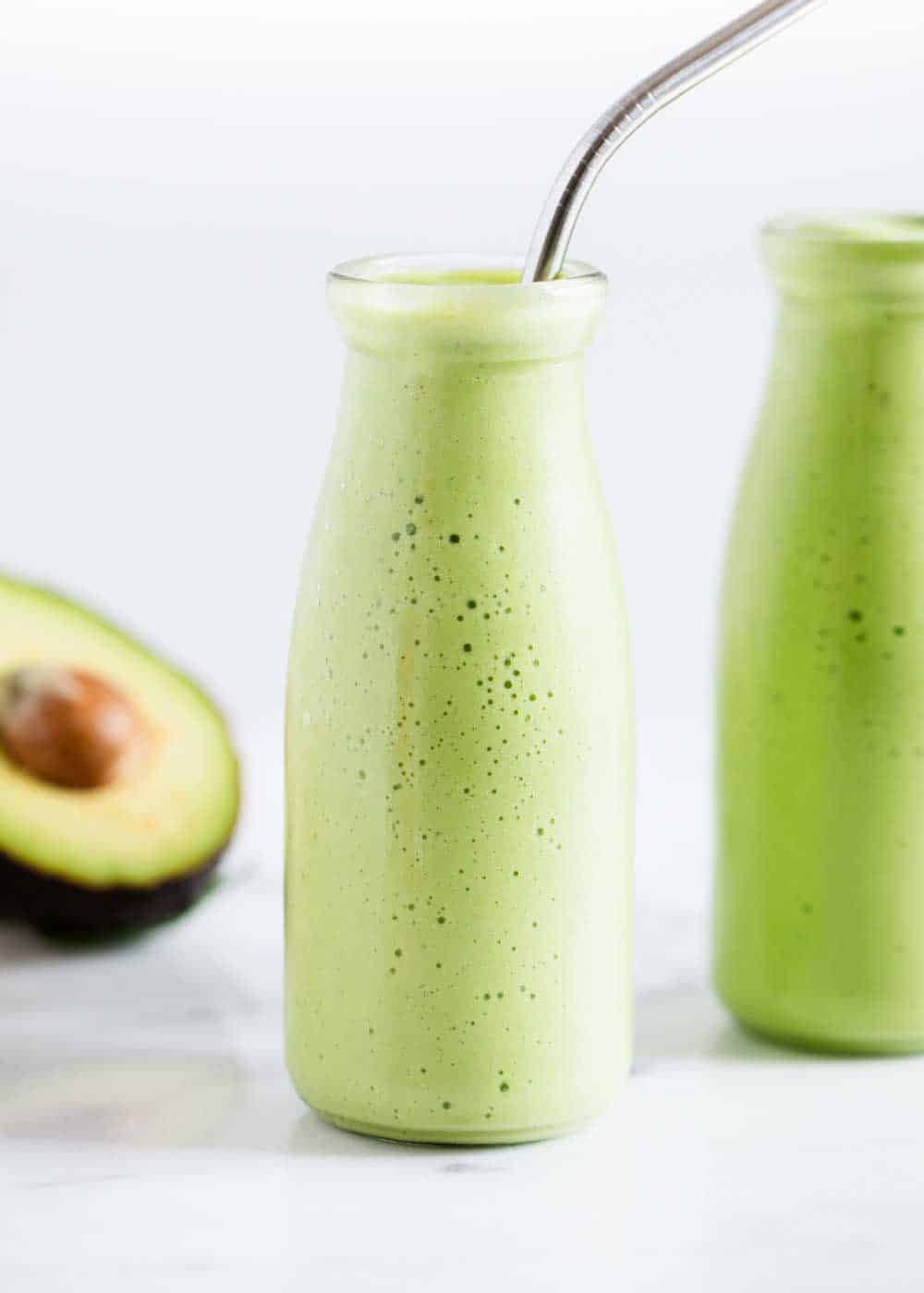 Avocado smoothie in glass jar with straw.