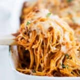 scooping baked spaghetti out of pan