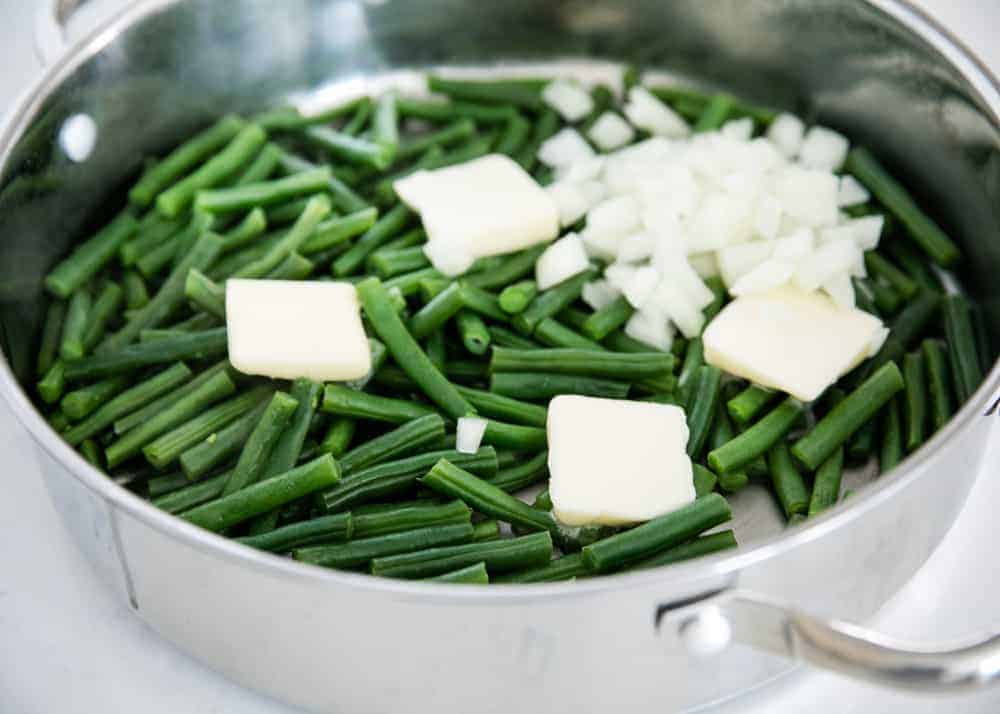 Cooking green beans and onions in a skillet with butter.