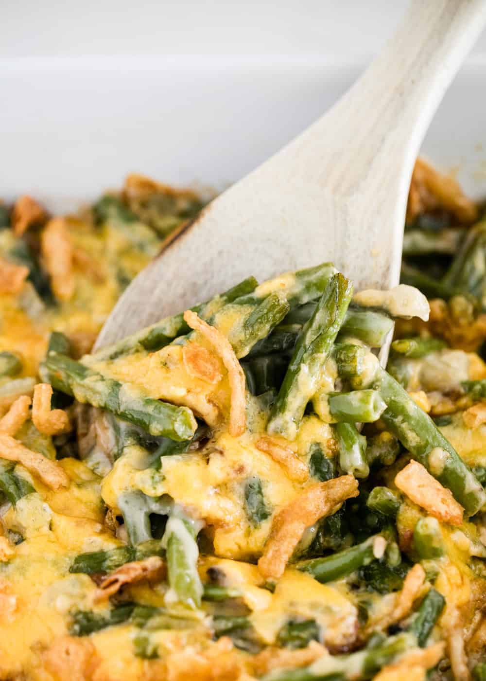 Green bean casserole served with wooden spoon.
